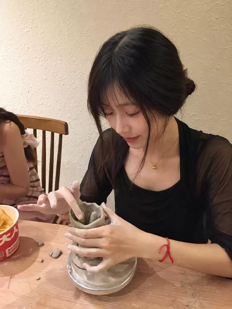 提示词：
以上传人物照片作为唯一身份与面部参考:生成一组真实自然的陶艺体验生活照。成年女性:长黑发